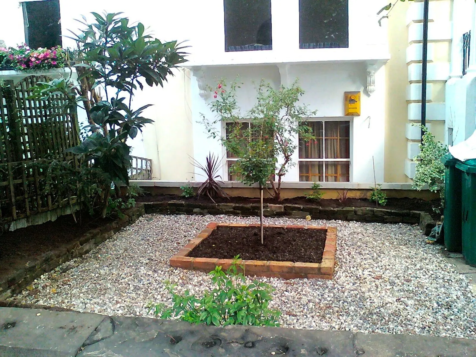 Front garden with a new sleeper raised bed, gravel and a young tree